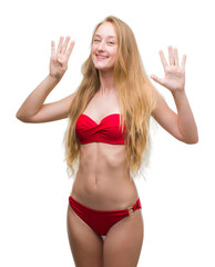 Blonde teenager woman wearing red bikini showing and pointing up with fingers number nine while...