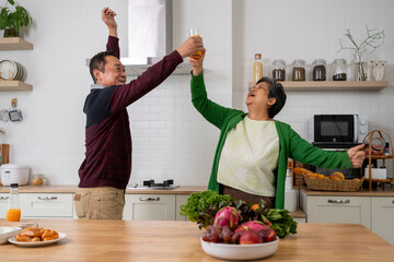 Cheerful Mature couple have fun to dancing together in kitchen