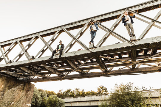 Group of friends walking across and hanging out on train bridge in the evening sun, Boho Style. Paarl, South Africa