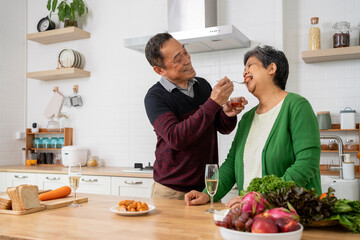 Mature couple have spending time with tasting sausage together in kitchen