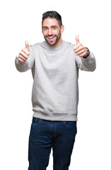 Young handsome man wearing sweatshirt over isolated background success sign doing positive gesture with hand, thumbs up smiling and happy. Looking at the camera with cheerful expression.
