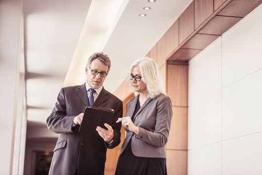Older business showing a colleague data on his tablet.