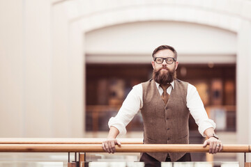 Caucasian business man standing casually in the office leaning on a railing.