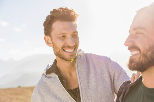 Two guys smiling at each other while hiking in the mountains.