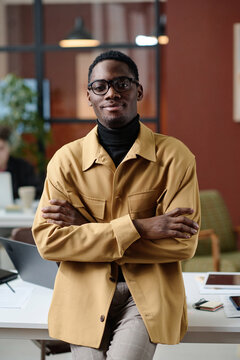 Young african american office worker in smart casual outfit confidently posing against his workplace