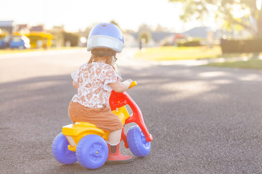 Aussie kid riding tricycle outside on quiet suburban road
