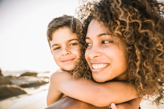 Mother with son on her back while at the beach at sunset.