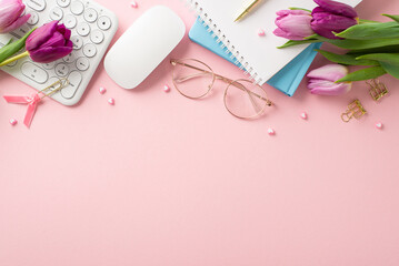 Corporate Celebration: top view desk adorned with chic essentials - keyboard, mouse, stylish glasses, notebooks, pen, clips, and fresh tulips on a soft pink backdrop. Ad space available