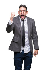 Young handsome business man over isolated background angry and mad raising fist frustrated and furious while shouting with anger. Rage and aggressive concept.