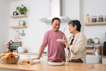 Cheerful Mature couple have spending time with fruit together in kitchen