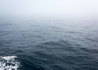 Russia Sakhalin Oblast 27.07.2023 Sea of Okhotsk in the fog. The line of the horizon, dissolving in the fog. The ship's footprint on the water. Space for text. Marine texture