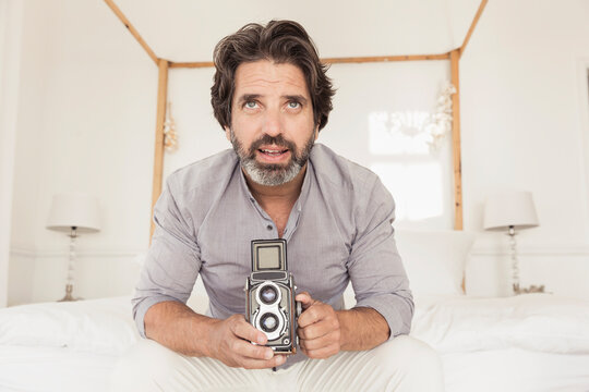 Man sitting on a bed using an analog camera