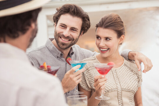 Two couples enjoying a cocktail at sunset on a beach house patio