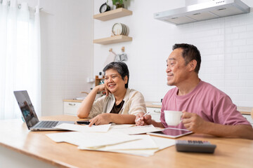 Happy Asian senior couple use digital technology device to working at home