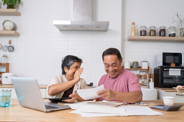 Happy Asian senior couple use digital technology device to working at home
