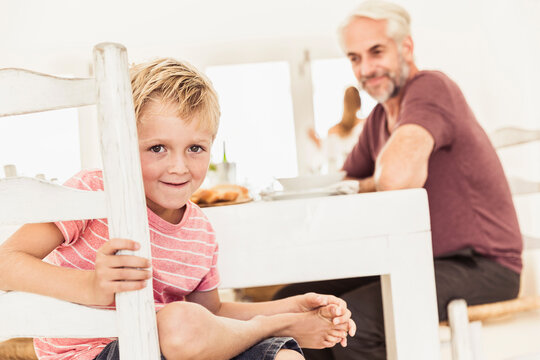 Young boy looking at the camera through his chair at the dinner table 