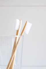 Stylish natural eco friendly toothbrushes with wooden bamboo handle in glass in bathroom. Oral hygiene concept. Copy space for text. Reduce plastic waste, sustainable lifestyle.