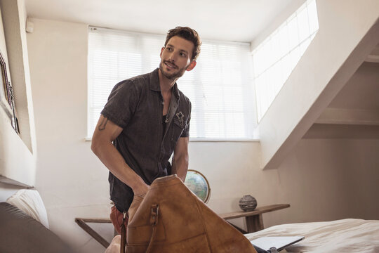 Man at home in his room packing his bag.