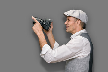 Young man with camera telling about key skills of photographer on gray background