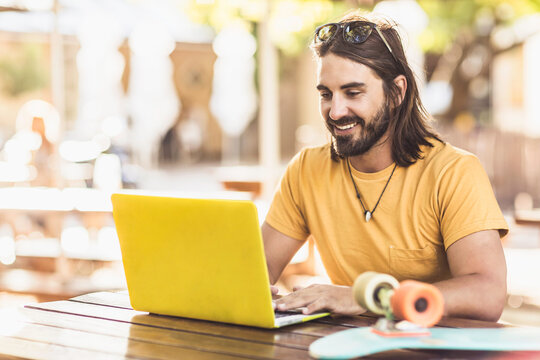 Happy guy on a laptop in an outdoor restaurant