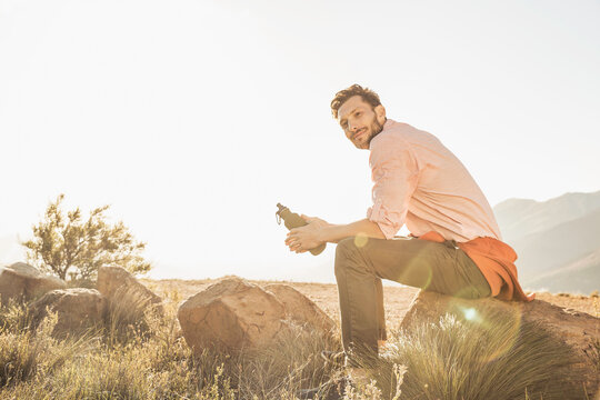 Guy relaxing in the mountains at sunset while hiking