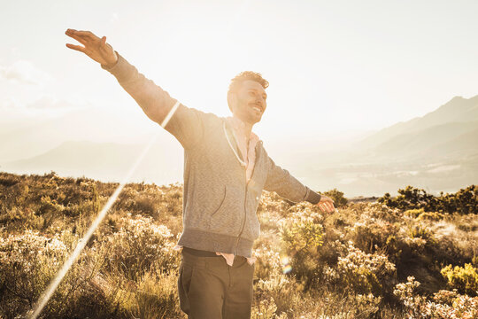 Happy guy dancing around in the mountains at sunset