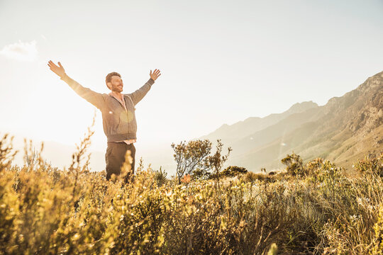 Happy guy dancing around in the mountains at sunset