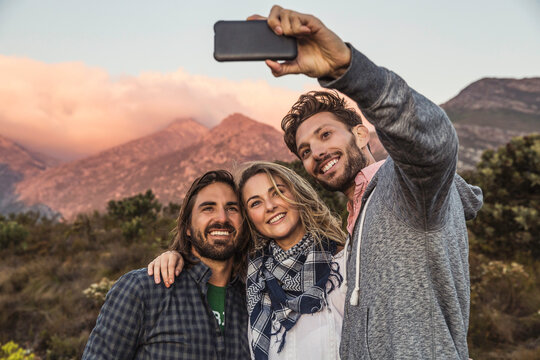 Group of friends taking a selfie in the mountains at sunset