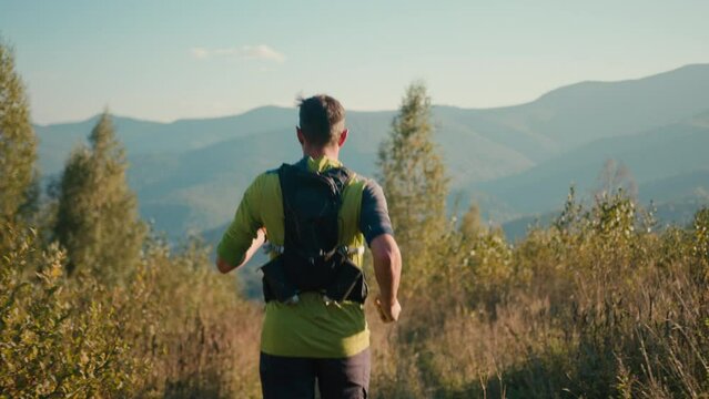 Back view focused Caucasian male man person runner guy mountaineer sportsman running jogging trail outside countryside meadow mountain hill sunshine. Sport motivation healthy lifestyle workout fitness