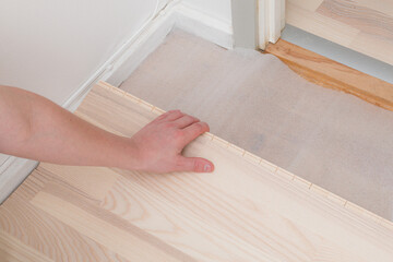 Professional worker installing new parquet flooring indoors, closeup