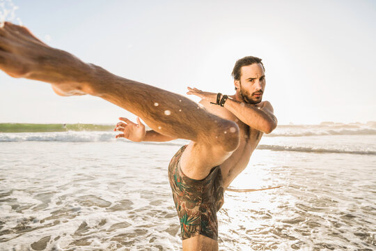 man practicing karate on a beach at sunset