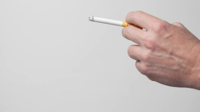 Smoking a cigarette. Male hand holding cigarette on white background