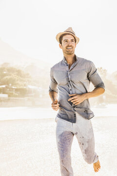 Man in pants and shirt walking and running along the beach