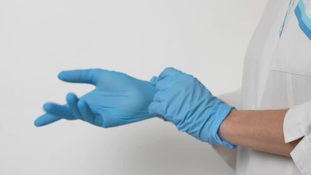 Female doctor putting on medical gloves against white background