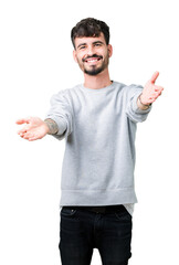 Naklejka premium Young handsome man wearing sweatshirt over isolated background looking at the camera smiling with open arms for hug. Cheerful expression embracing happiness.