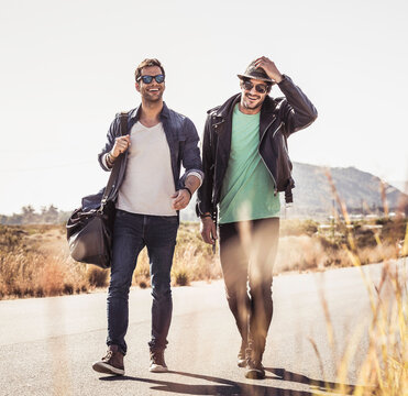 Group of guys walking along a road while hitch hiking.