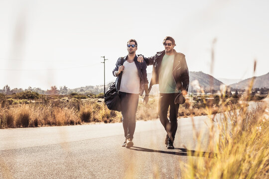 Group of guys walking along a road while hitch hiking.