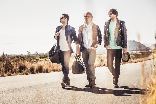 Group of guys walking along a road while hitch hiking.