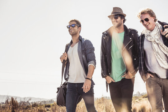 Group of guys walking along a road while hitch hiking.