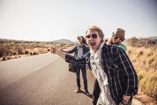 Group of guys walking along a road while hitch hiking.
