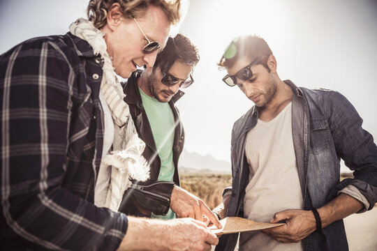 Group of guys walking along a road while hitch hiking.