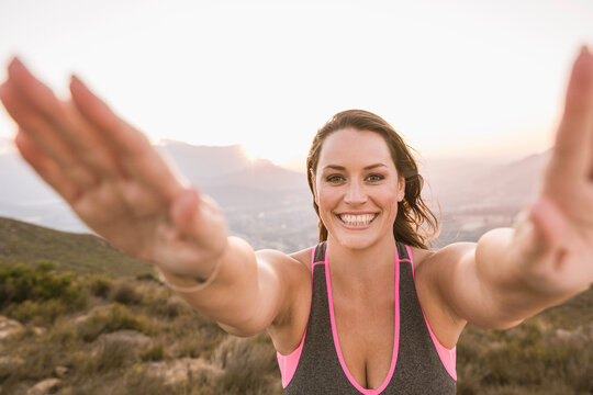 Beautiful overweight woman exercising on a mountain at sunset