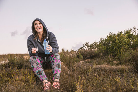 Beautiful overweight woman exercising on a mountain at sunset