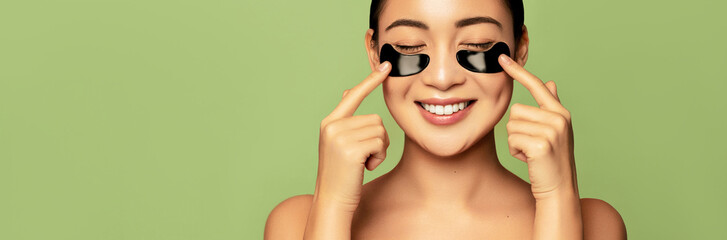Skin care eye patches. Asian beauty care concept. Beautiful model applying black hydro gel collagen...