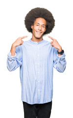 Young african american man with afro hair smiling confident showing and pointing with fingers teeth and mouth. Health concept.