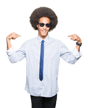 Young african american business man with afro hair wearing sunglasses looking confident with smile on face, pointing oneself with fingers proud and happy.
