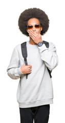 Young african american man with afro hair wearing sunglasses and backpack cover mouth with hand shocked with shame for mistake, expression of fear, scared in silence, secret concept