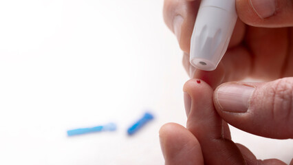 Caucasian middle aged man pierced his finger for home glucose test with lancet needles at...