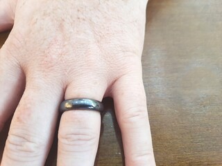 Obraz premium Hematite ring or band on a man's finger. It is believed that the use of hematite stimulates courage and determination, protects against negative energy, helps cleanse the blood, among other benefits.
