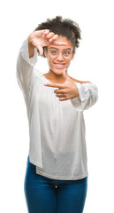 Young afro american woman wearing glasses over isolated background smiling making frame with hands and fingers with happy face. Creativity and photography concept.